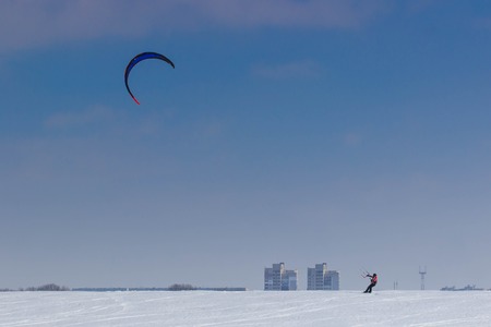 A snowboarder with a kite rides on a frozen lake on free rideの写真素材