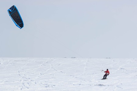 A snowboarder with a kite rides on a frozen lake on free rideの写真素材