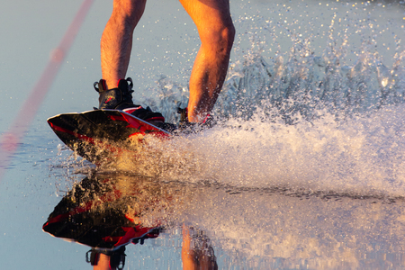 Men's feet on a wakeboard in water.guy sitting by the river and is preparing to go wake boardingの写真素材