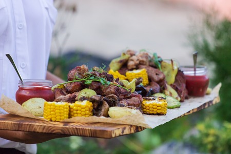 Waiter is offering grilled meat and vegetables.の写真素材