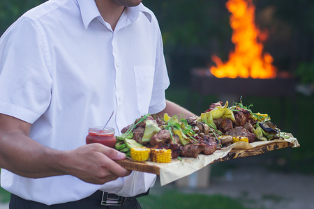 Waiter is offering grilled meat and vegetables.の写真素材