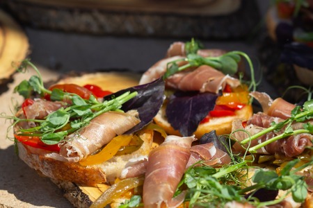 Close up bruschetta with proschuto, tomato, parmesan cheese and arugula.の写真素材