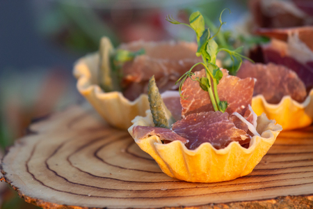 exquisite beautiful serve prosciutto in baskets on a wooden slice. Cateringの写真素材