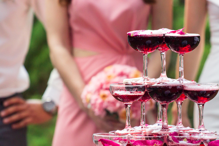 A pyramid of champagne glasses with a rose petals.の写真素材