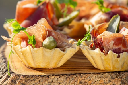 exquisite beautiful serve prosciutto in baskets on a wooden slice. Cateringの写真素材