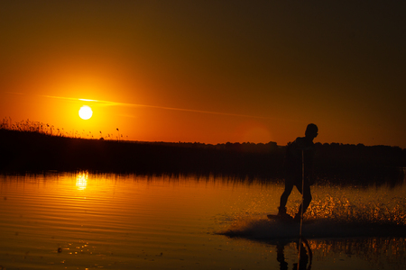Wakeboarder making tricks on sunsetの写真素材
