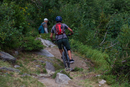 Cyclist in Red Riding the Bike on the Autumn Rocky Trail at Sunset. Extreme Sport and Enduro Biking...