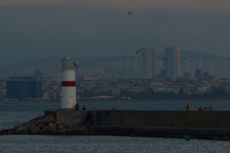 Seaside view with water waves, rocks, a lot of birds and lighthouse in eminonu, istanbul, turkeyの写真素材
