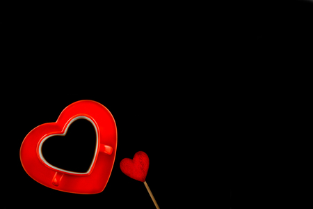 Red heart cup with wooden homemade hearts and coffee. Black background. Valentine day concept.の写真素材