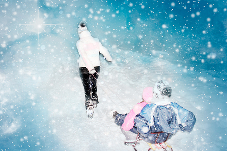 Little girls enjoying sledding. Father sledding his little adorable daughters. Family vacation on Christmas eve outdoors.の写真素材