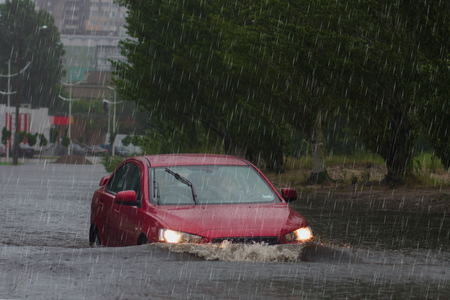 car rides in heavy rain on a flooded roadの写真素材
