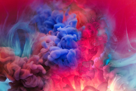powder in different colours thrown into the air forming a huge cloud of smoke with little bits.の写真素材