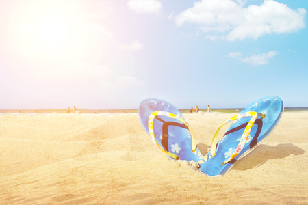 Blue sandal flip flop on the white sand beach with blue sea and sky background in summer vacationsの写真素材