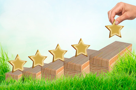 Hand putting wooden five star shape on table. The best excellent business services rating customer...