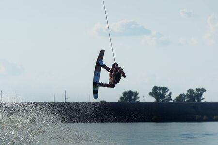 Cherkassy, Ukraine - July 19, 2019: Wakeboarder showing of tricks and skills at wakeboarding reverse...