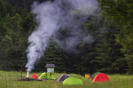 Tent camping car couple romantic sitting by bonfire night countryside. Smoke