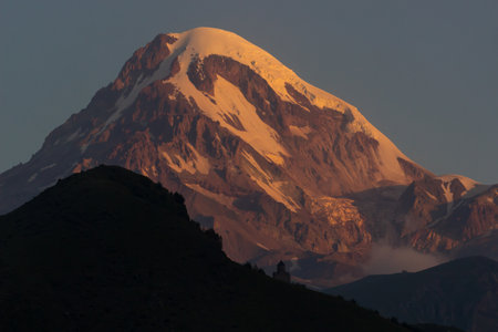 Distant view on Gergeti Trinity Church in Stepansminda, Georgia. Clear sky above the snow-capped...
