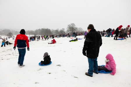 LONDON, UNITED KINGDOM - JANUARY 20, 2013: Families make the most of the unusual snowy weather in London and enjoy sledding down Parliament Hill on Hampstead Heathのeditorial素材