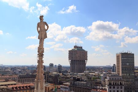 Cathedral statue and view of Milan cityscape with Torre Valescaの写真素材