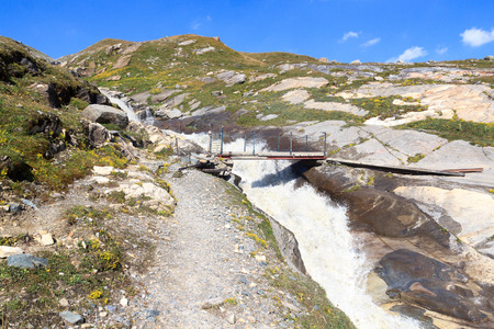 Rapid stream, bridge and mountain panorama in Hohe Tauern Alps, Austriaの写真素材