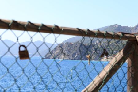 Padlocks and rocky coast with Cinque Terre village Corniglia and Mediterranean Sea, Italyの写真素材