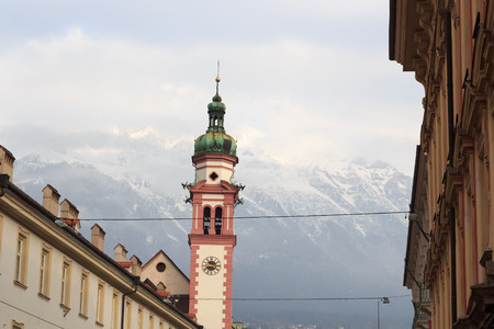 Innsbruck cityscape with church spire and snow mountains, Austriaの写真素材
