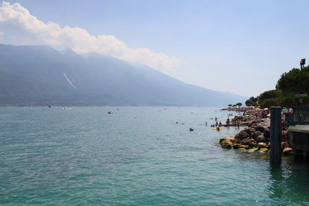 Lake Garda and mountain panorama with boats and bathing people in Limone, Italyのeditorial素材