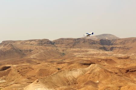 Judaean Desert mountain panorama with wadis and airplane seen from Masada fortress, Israel