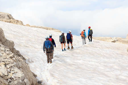 People hiking on snow field in Brenta Dolomites mountains, Italy