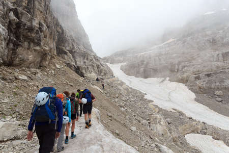 People hiking towards col Bocca del Tuckett on snow field in Brenta Dolomites mountains, Italyのeditorial素材
