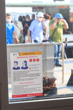Venice, Italy - August 10, 2020: Coronavirus warning sign and people wearing masks at Actv vaporetto waterbus station. During the COVID-19 pandemic it is obligatory to wear masks in public transport.のeditorial素材