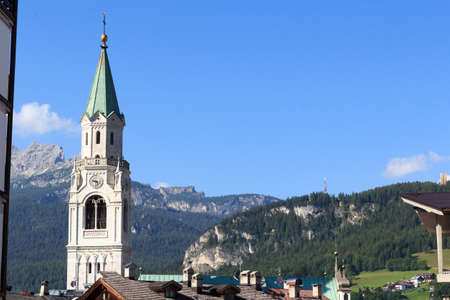 Basilica church steeple and mountain panorama view in Cortina d'Ampezzo, Italyの写真素材