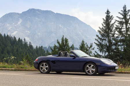 Berchtesgaden, Germany - July 24, 2021: Blue roadster Porsche Boxster 986 with mountain Hoher Goell...