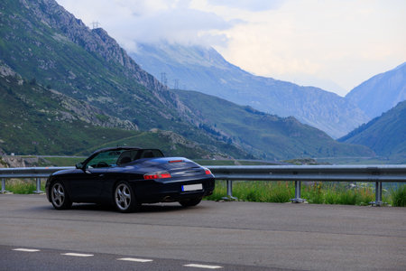Hospental, Switzerland - July 5, 2025: Blue Porsche 911 convertible on mountain pass Gotthard Pass...