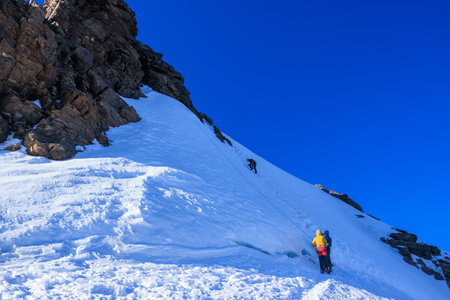 Mountaineer climbing top-rope the summit Corno Nero (Schwarzhorn) on mountain Monte Rosa massif with...