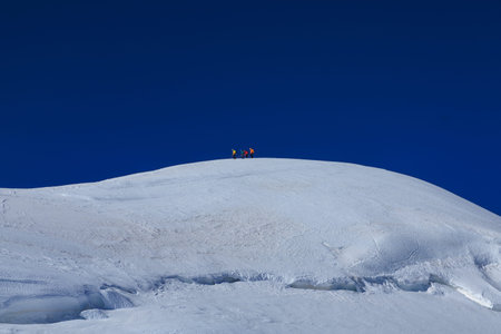 Mountaineers in rope team with crampons descending from summit Parrotspitze on mountain massif Monte...