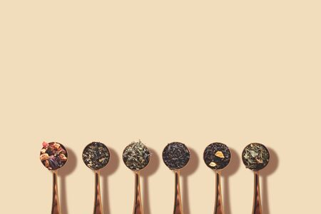Spoons with assortment of tea on beige background with shadowの写真素材
