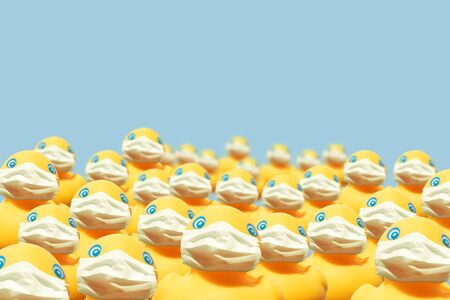 Virus spread prevention concept: yellow rubber duck wearing surgical face masks on blue background with copy spaceの写真素材
