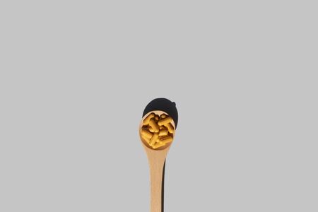 super food concept wooden spoon with turmeric curcumin capsules on grey backgroundの写真素材