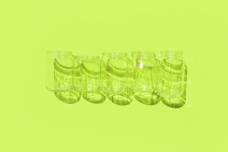recycling or zero waste concept empty glass bottles with shadows on grass green backgroundの写真素材