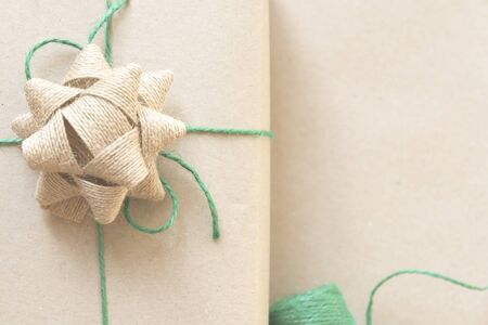 zero waste christmas concept present wrapped in plain recycled paper with burlap ribbon, green...