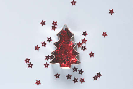 Christmas tree shape cookie cutter with red star confetti on blue background festive xmas cardの写真素材