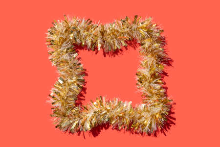 golden tinsel frame on a coral red background for Christmas cardの写真素材
