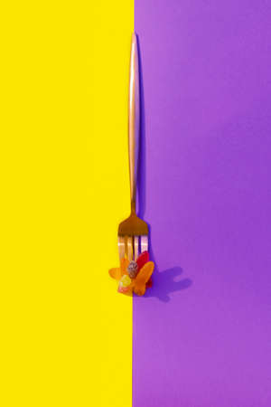 metalic fork with jelly worms on a vertical yellow and purple color block background for halloweenの写真素材