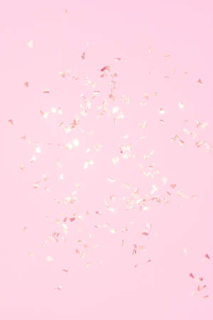 gold shiny flying confetti on a pink background festive backdrop for any christmas projectの写真素材