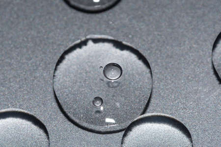 transparent gel texture droplets on a metallic silver background beauty treatment conceptの写真素材