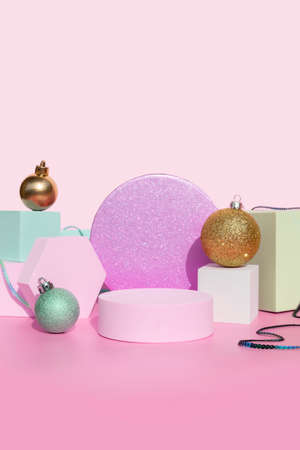 coral pink podium with geometric shapes background and gold and blue Christmas balls for product...