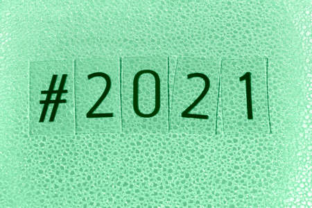hashtag 2021 on a shiny textured paper background new year card toned green ash