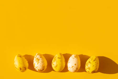 yellow and white Easter eggs painted with gold with graphic shadow on a bright saturated yellow...