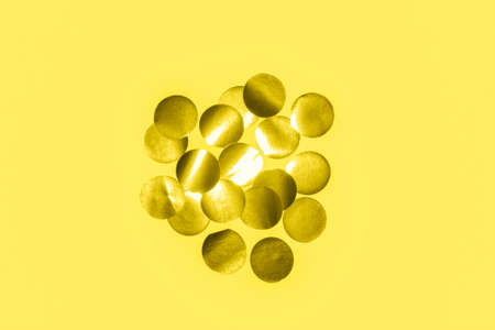 metallic round confetti pattern on a pastel yellow background toned trendy color illuminatingの写真素材
